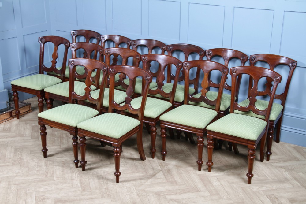 A set of fourteen Victorian mahogany dining chairs featuring carved crown splats, turned front legs, and green patterned upholstered seats. View VII