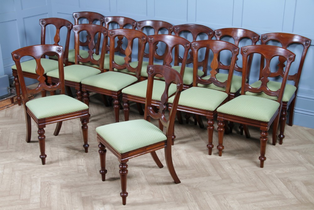 A set of fourteen Victorian mahogany dining chairs featuring carved crown splats, turned front legs, and green patterned upholstered seats. View VIII