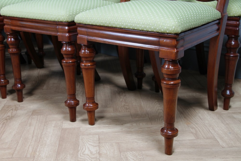 A set of fourteen Victorian mahogany dining chairs featuring carved crown splats, turned front legs, and green patterned upholstered seats. View XI