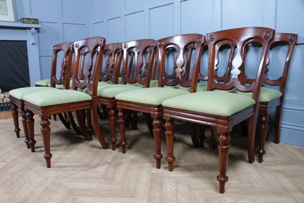 A set of fourteen Victorian mahogany dining chairs featuring carved crown splats, turned front legs, and green patterned upholstered seats. View XII