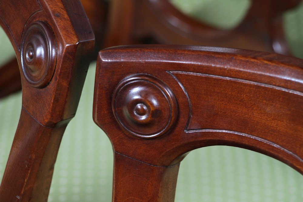A set of fourteen Victorian mahogany dining chairs featuring carved crown splats, turned front legs, and green patterned upholstered seats. View XIII