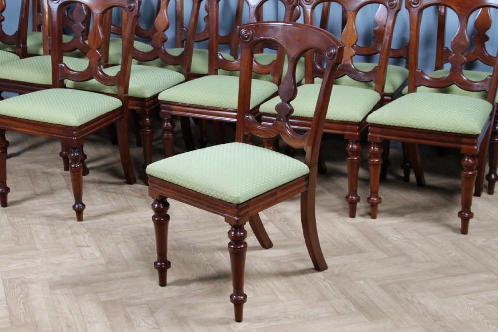 A set of fourteen Victorian mahogany dining chairs featuring carved crown splats, turned front legs, and green patterned upholstered seats. View XIV
