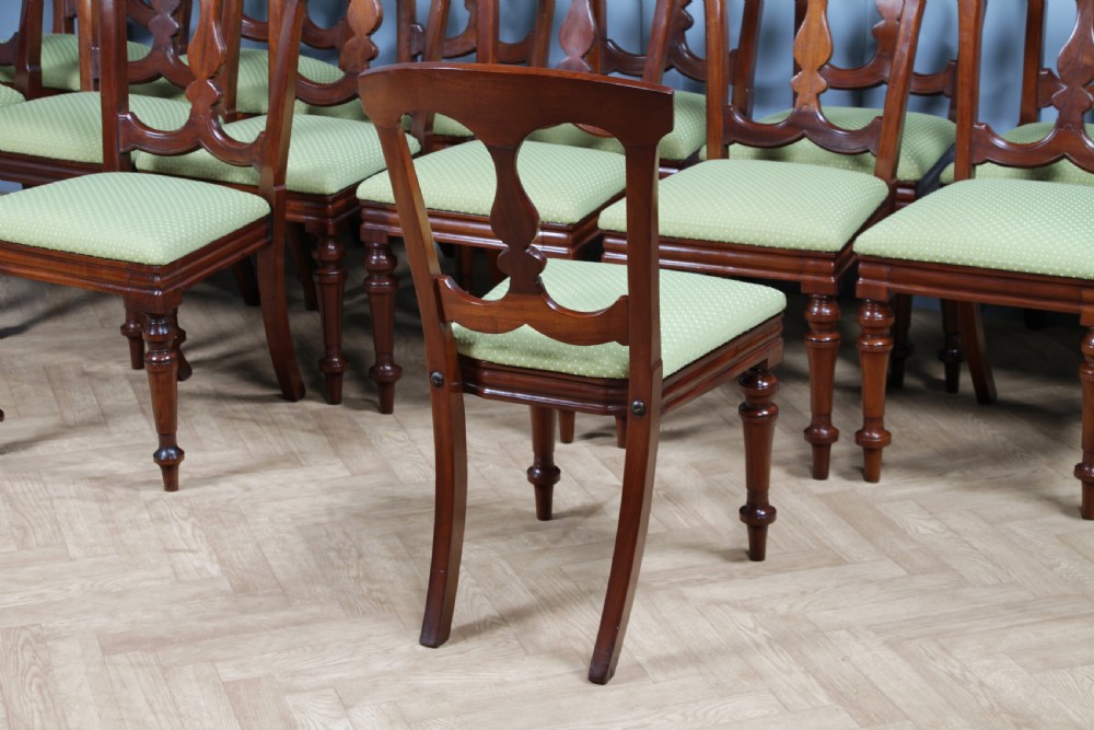 A set of fourteen Victorian mahogany dining chairs featuring carved crown splats, turned front legs, and green patterned upholstered seats. View XVI