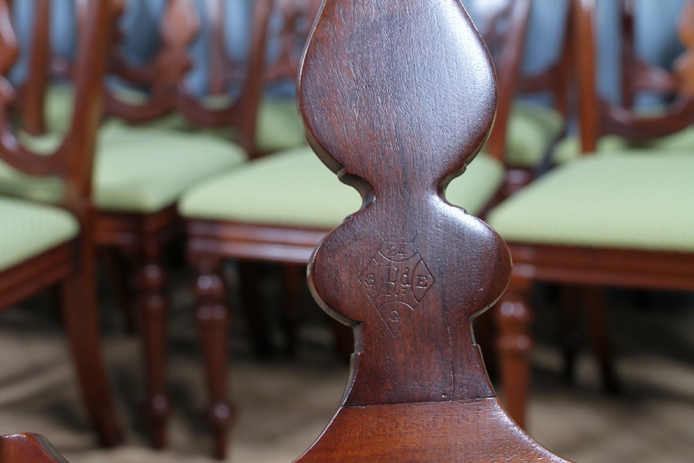 A set of fourteen Victorian mahogany dining chairs featuring carved crown splats, turned front legs, and green patterned upholstered seats. View XVII