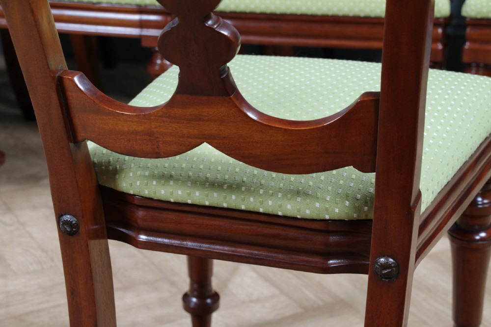 A set of fourteen Victorian mahogany dining chairs featuring carved crown splats, turned front legs, and green patterned upholstered seats. View XVIII