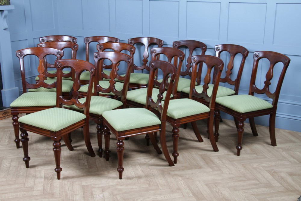 A set of fourteen Victorian mahogany dining chairs featuring carved crown splats, turned front legs, and green patterned upholstered seats. View XIX
