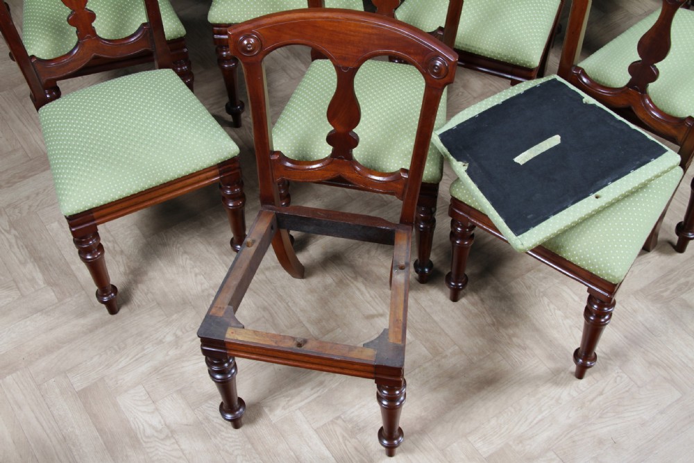 A set of fourteen Victorian mahogany dining chairs featuring carved crown splats, turned front legs, and green patterned upholstered seats. View XXI