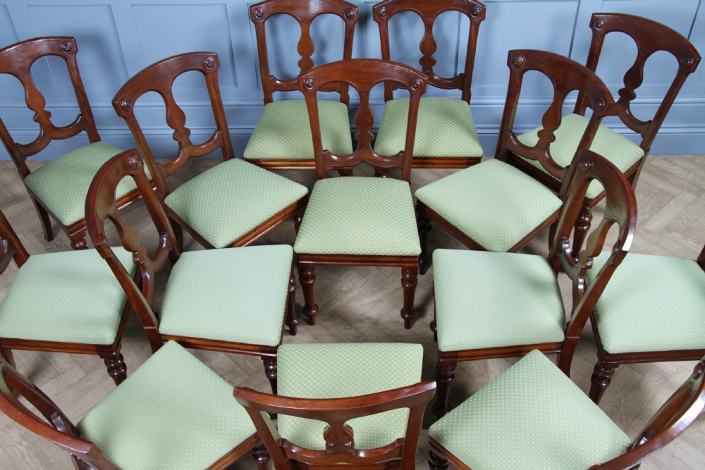 A set of fourteen Victorian mahogany dining chairs featuring carved crown splats, turned front legs, and green patterned upholstered seats. View XXII
