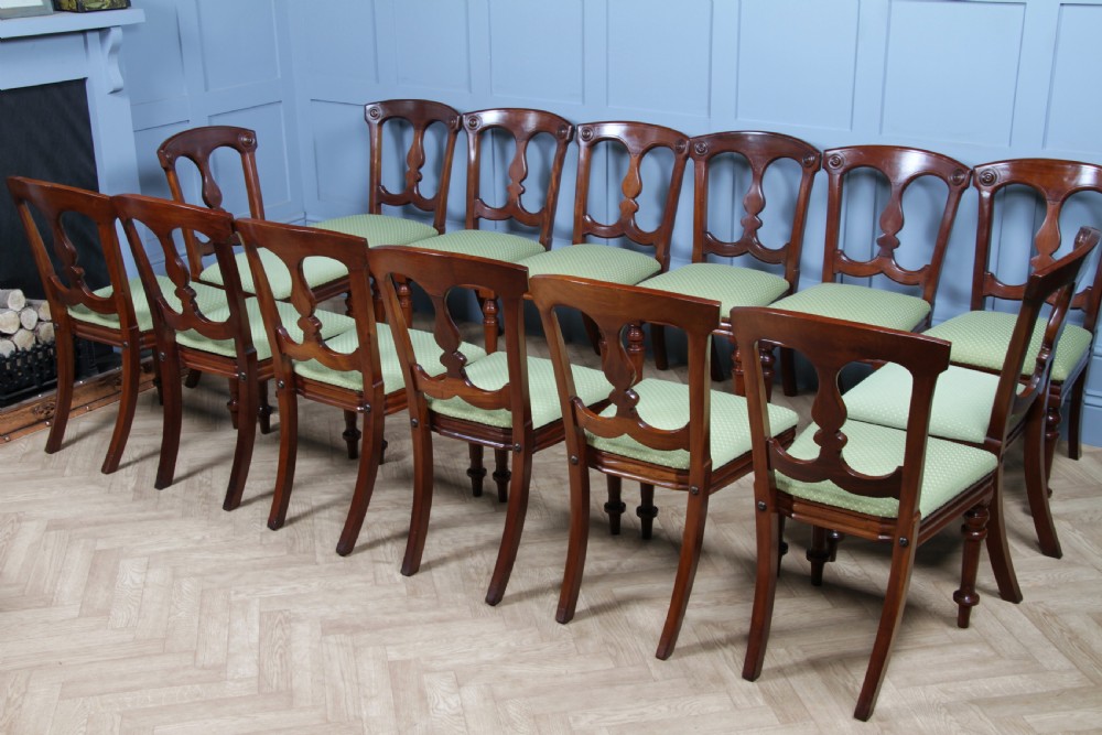 A set of fourteen Victorian mahogany dining chairs featuring carved crown splats, turned front legs, and green patterned upholstered seats. View XXIII