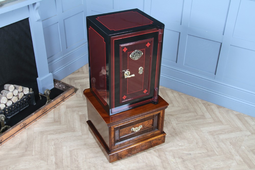 A restored black and burgundy Victorian Chubb safe with brass hardware resting atop a dark burr walnut wooden stand with a single drawer. View II