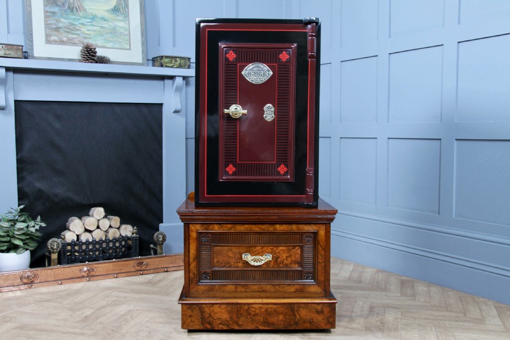 A restored black and burgundy Victorian Chubb safe with brass hardware resting atop a dark burr walnut wooden stand with a single drawer. View III