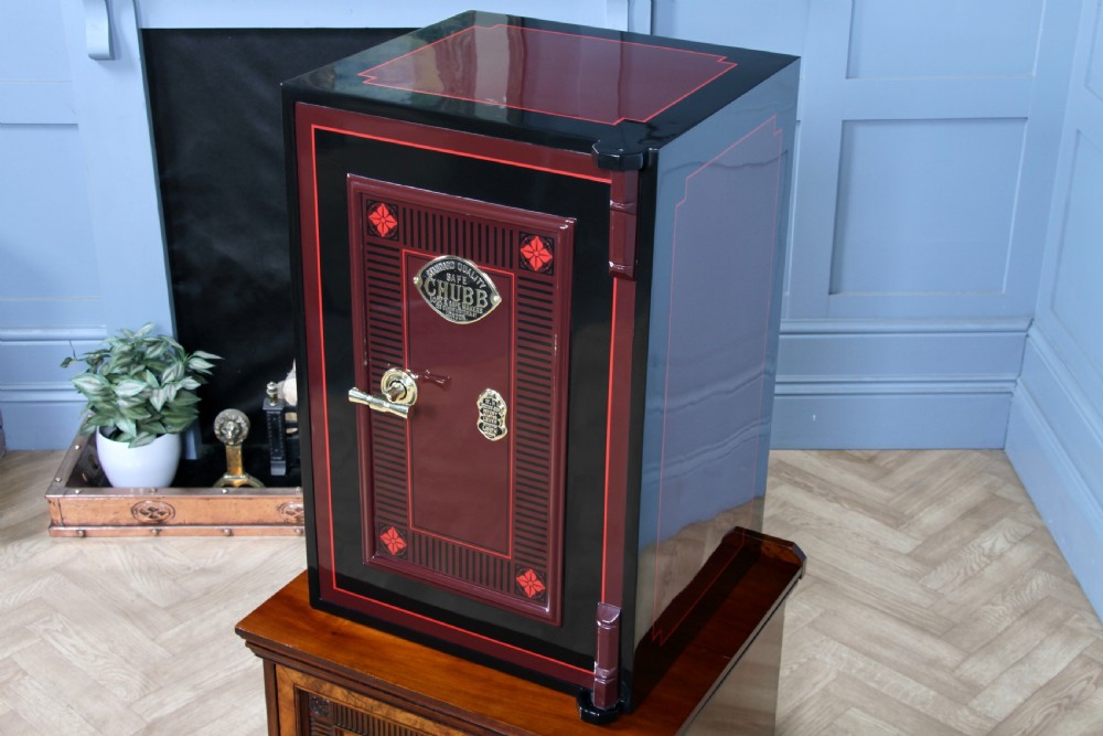 A restored black and burgundy Victorian Chubb safe with brass hardware resting atop a dark burr walnut wooden stand with a single drawer. View XI