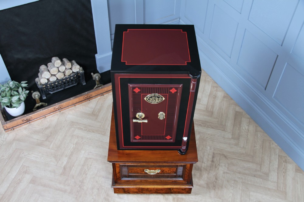 A restored black and burgundy Victorian Chubb safe with brass hardware resting atop a dark burr walnut wooden stand with a single drawer. View XII