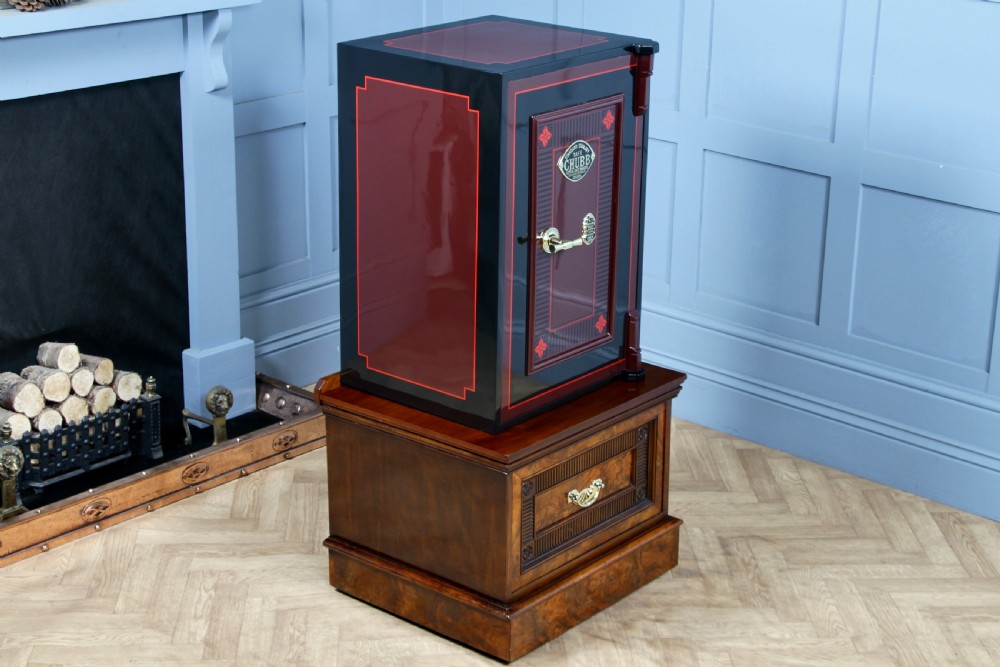 A restored black and burgundy Victorian Chubb safe with brass hardware resting atop a dark burr walnut wooden stand with a single drawer. View XIV