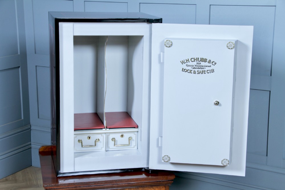 A restored black and burgundy Victorian Chubb safe with brass hardware resting atop a dark burr walnut wooden stand with a single drawer. View XVI