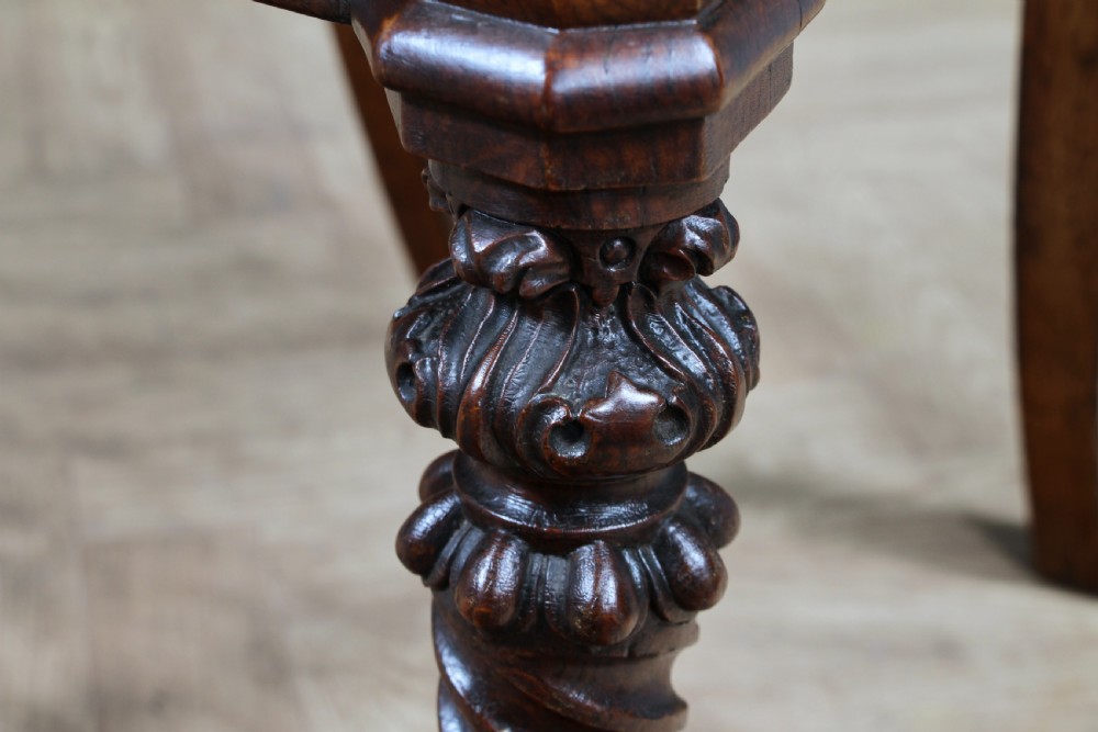 An antique carved dark oak hall chair featuring a decorative backrest with a central crest motif, finials, and barley twist front legs. View X
