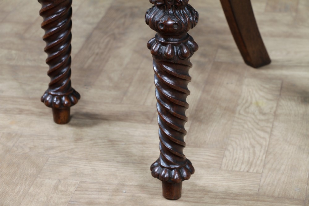An antique carved dark oak hall chair featuring a decorative backrest with a central crest motif, finials, and barley twist front legs. View XXII