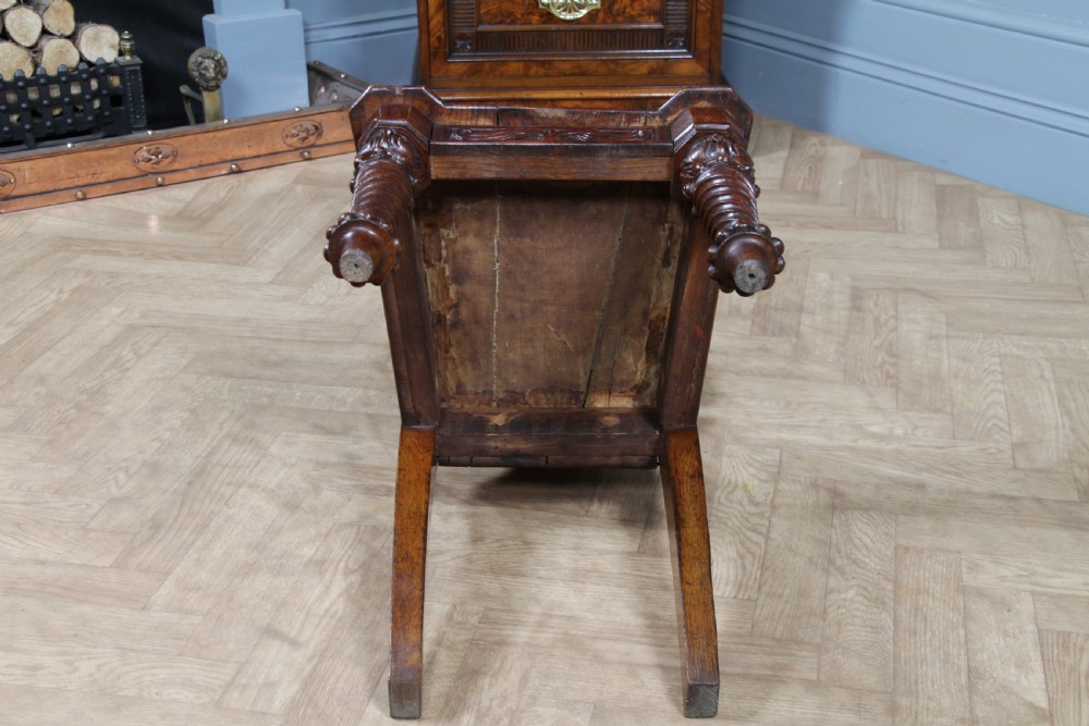 An antique carved dark oak hall chair featuring a decorative backrest with a central crest motif, finials, and barley twist front legs. View XXIV