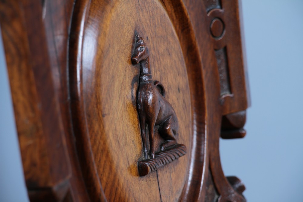 An antique carved dark oak hall chair featuring a decorative backrest with a central crest motif, finials, and barley twist front legs. View XXV