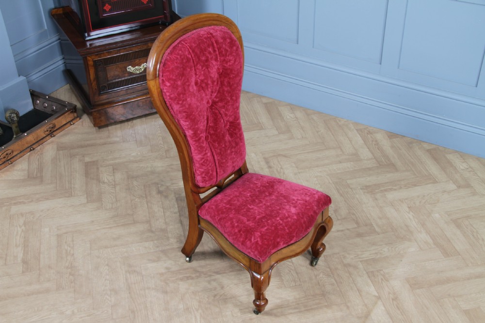 A Victorian walnut nursing chair featuring a tall balloon back with deep-buttoned magenta velvet upholstery and cabriole front legs on brass castors. View IX