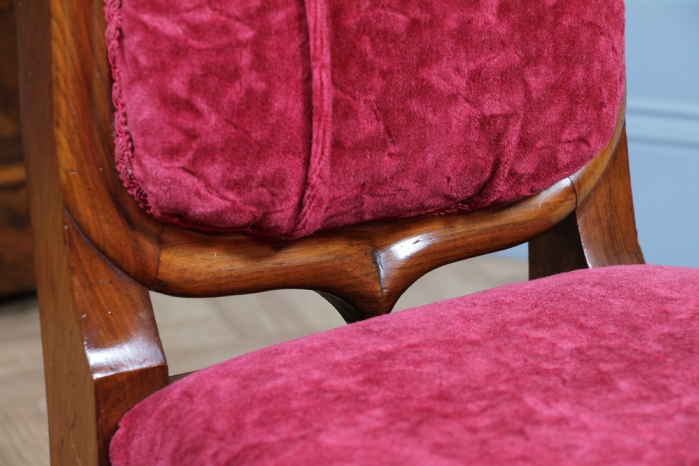 A Victorian walnut nursing chair featuring a tall balloon back with deep-buttoned magenta velvet upholstery and cabriole front legs on brass castors. View XI