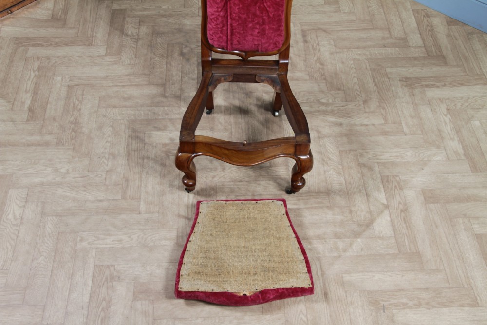 A Victorian walnut nursing chair featuring a tall balloon back with deep-buttoned magenta velvet upholstery and cabriole front legs on brass castors. View XIV