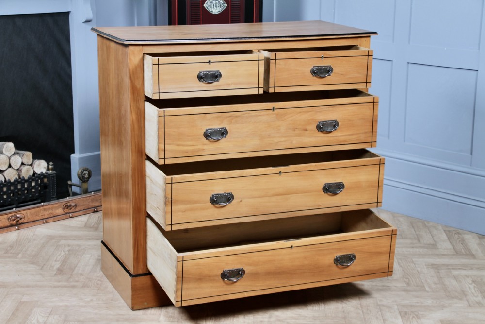 A late Victorian satinwood chest featuring two short drawers above three long drawers with ebonised stringing and dark metal handles on a solid plinth base. View II
