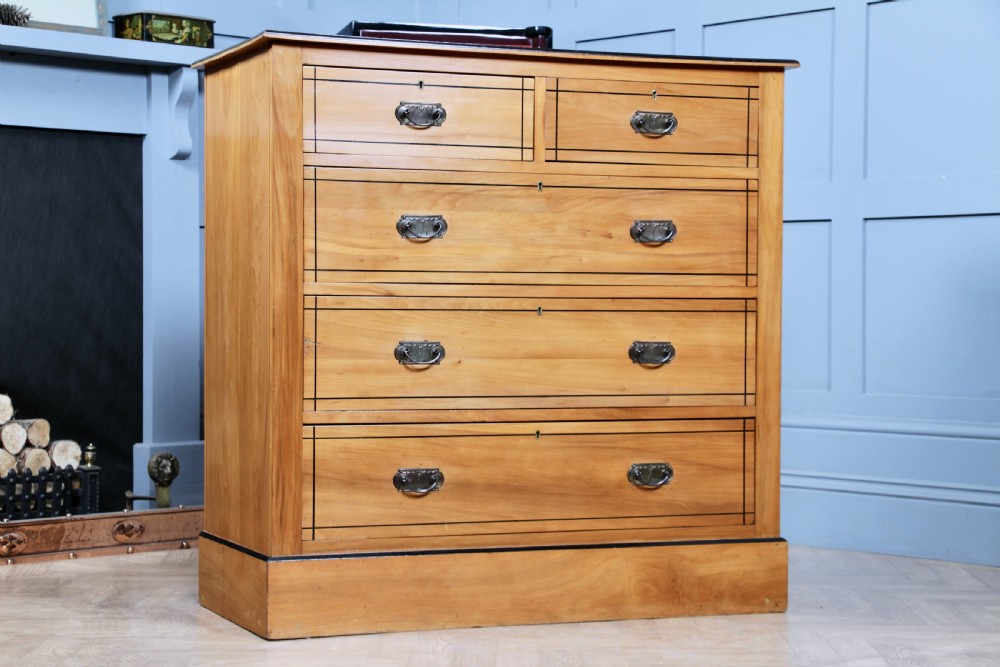 A late Victorian satinwood chest featuring two short drawers above three long drawers with ebonised stringing and dark metal handles on a solid plinth base. View III