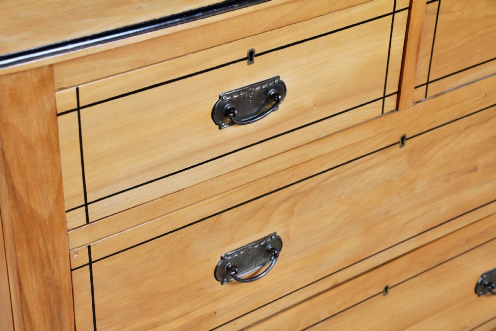 A late Victorian satinwood chest featuring two short drawers above three long drawers with ebonised stringing and dark metal handles on a solid plinth base. View VII