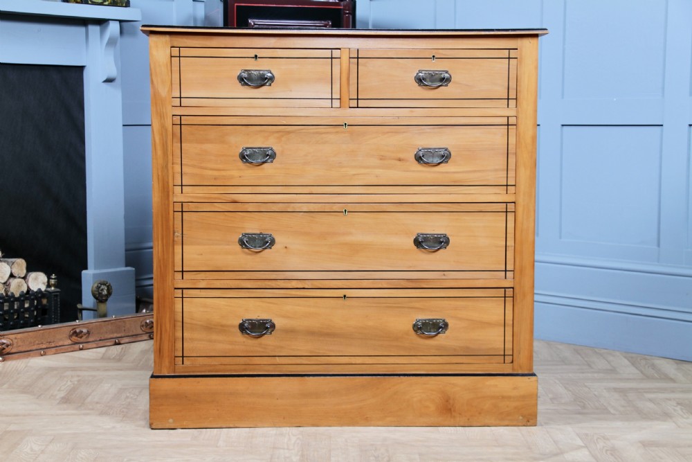 A late Victorian satinwood chest featuring two short drawers above three long drawers with ebonised stringing and dark metal handles on a solid plinth base. View VIII