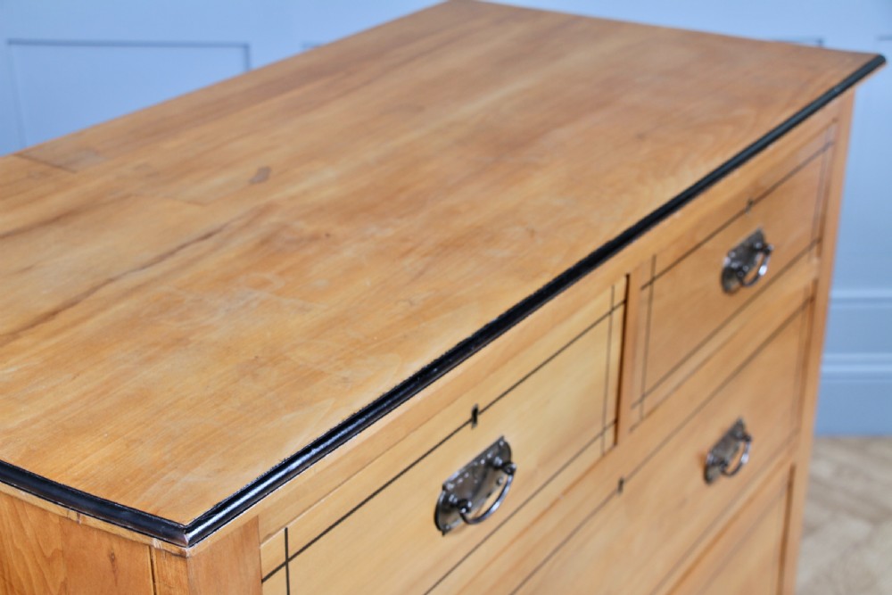 A late Victorian satinwood chest featuring two short drawers above three long drawers with ebonised stringing and dark metal handles on a solid plinth base. View IX