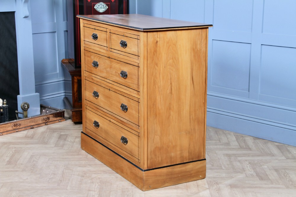 A late Victorian satinwood chest featuring two short drawers above three long drawers with ebonised stringing and dark metal handles on a solid plinth base. View X