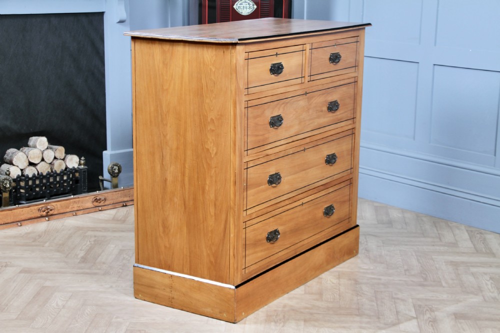 A late Victorian satinwood chest featuring two short drawers above three long drawers with ebonised stringing and dark metal handles on a solid plinth base. View XI