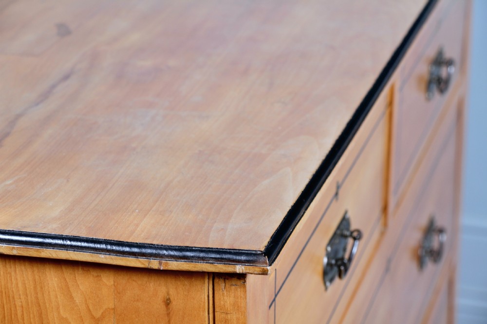 A late Victorian satinwood chest featuring two short drawers above three long drawers with ebonised stringing and dark metal handles on a solid plinth base. View XII