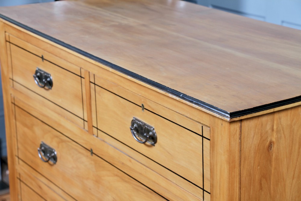 A late Victorian satinwood chest featuring two short drawers above three long drawers with ebonised stringing and dark metal handles on a solid plinth base. View XIII