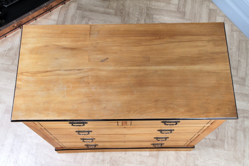 A late Victorian satinwood chest featuring two short drawers above three long drawers with ebonised stringing and dark metal handles on a solid plinth base. View XIV