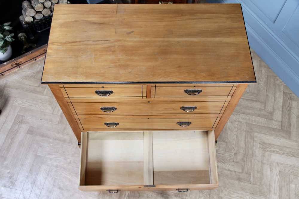 A late Victorian satinwood chest featuring two short drawers above three long drawers with ebonised stringing and dark metal handles on a solid plinth base. View XIX