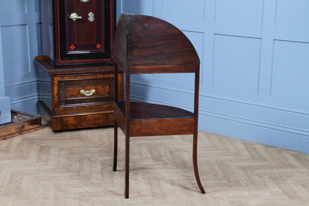 An antique dark mahogany corner washstand featuring a curved splashback with a small top shelf, a middle surface tier, a lower shelf with a central drawer, and splayed legs. View XXII
