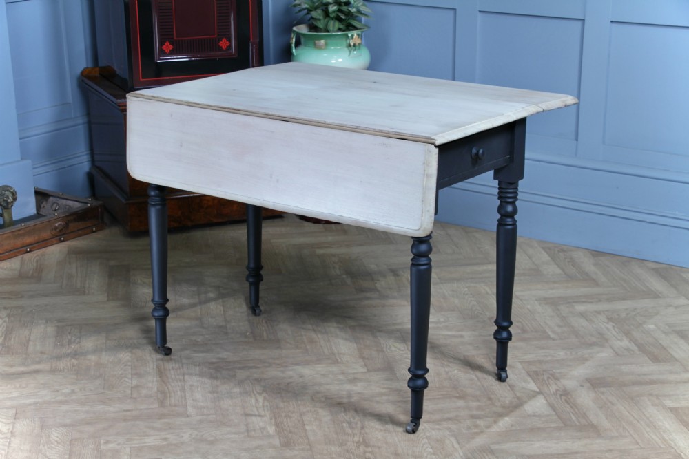 A restored Victorian Pembroke table featuring a bleached mahogany drop-leaf top and a black painted frame with turned legs on brass castors. View II