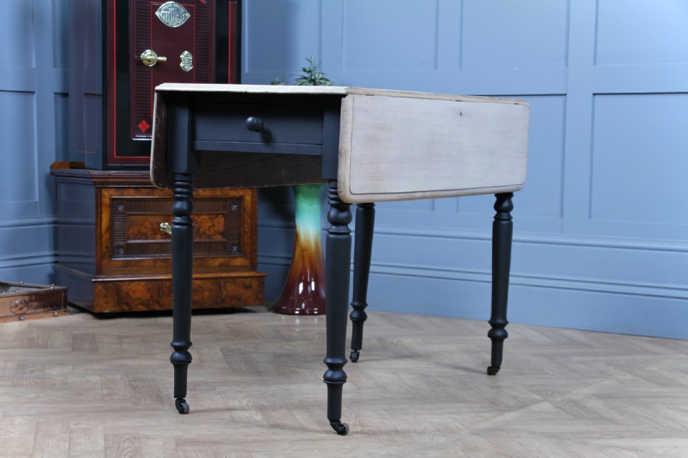 A restored Victorian Pembroke table featuring a bleached mahogany drop-leaf top and a black painted frame with turned legs on brass castors. View VII