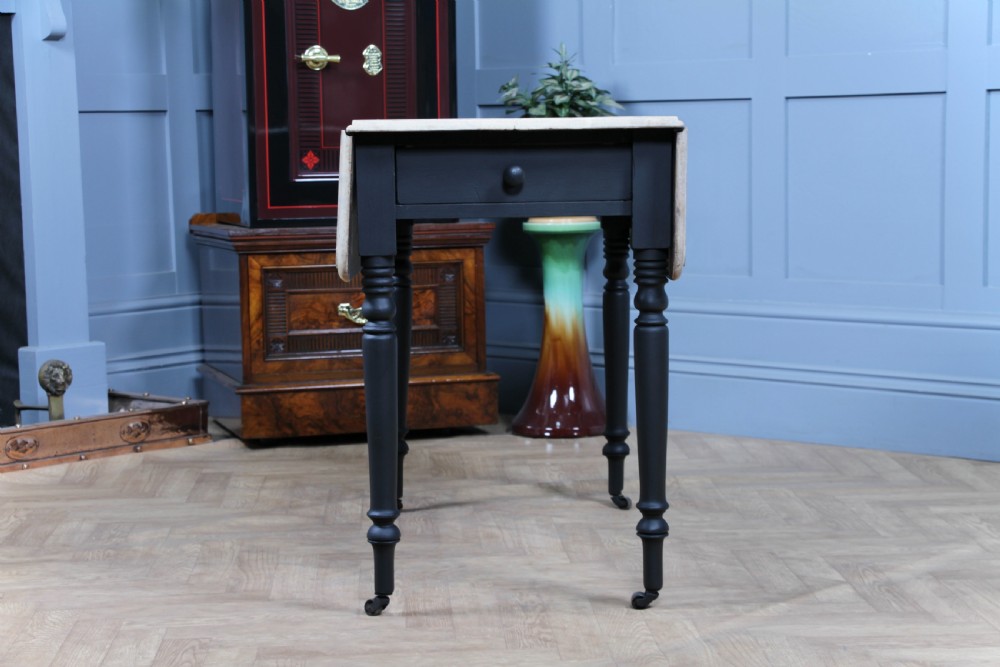 A restored Victorian Pembroke table featuring a bleached mahogany drop-leaf top and a black painted frame with turned legs on brass castors. View VIII