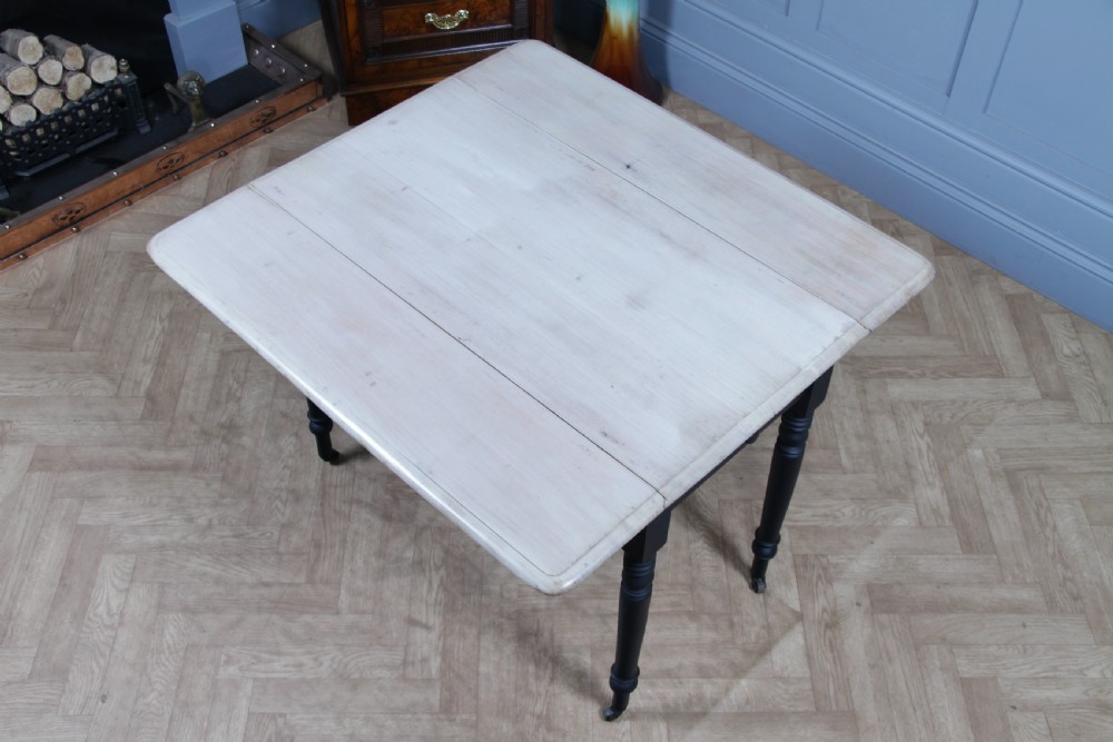 A restored Victorian Pembroke table featuring a bleached mahogany drop-leaf top and a black painted frame with turned legs on brass castors. View IX