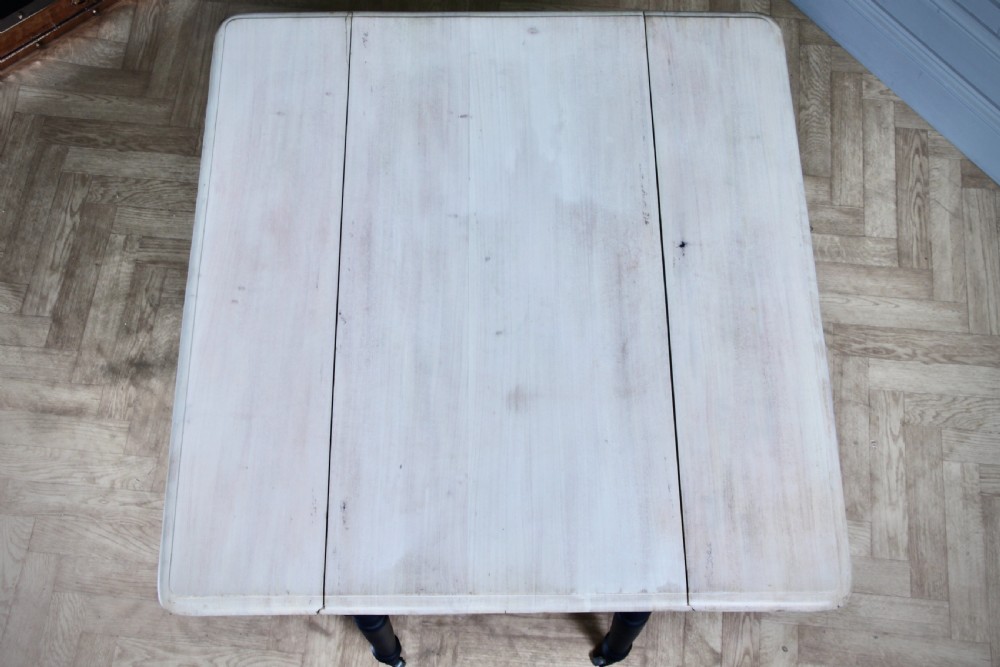 A restored Victorian Pembroke table featuring a bleached mahogany drop-leaf top and a black painted frame with turned legs on brass castors. View XI