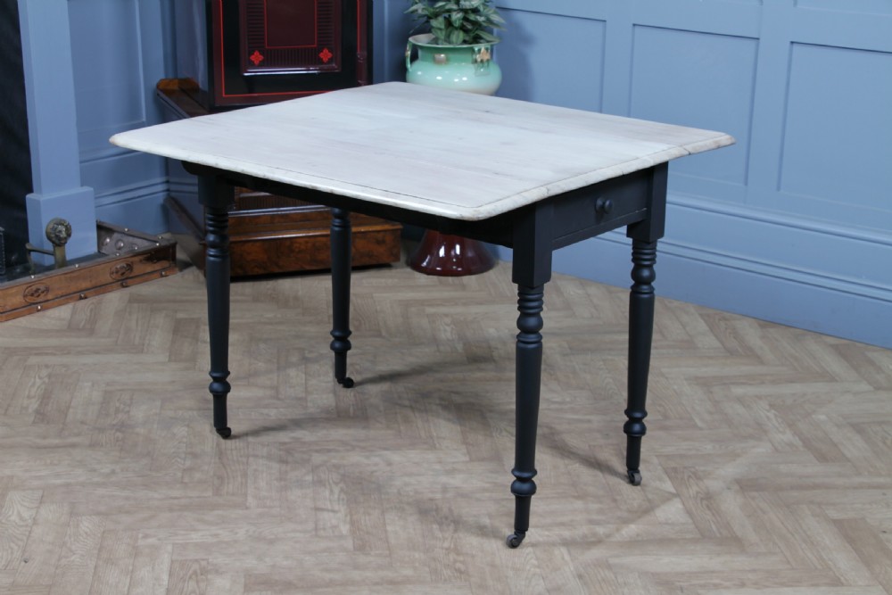 A restored Victorian Pembroke table featuring a bleached mahogany drop-leaf top and a black painted frame with turned legs on brass castors. View XII