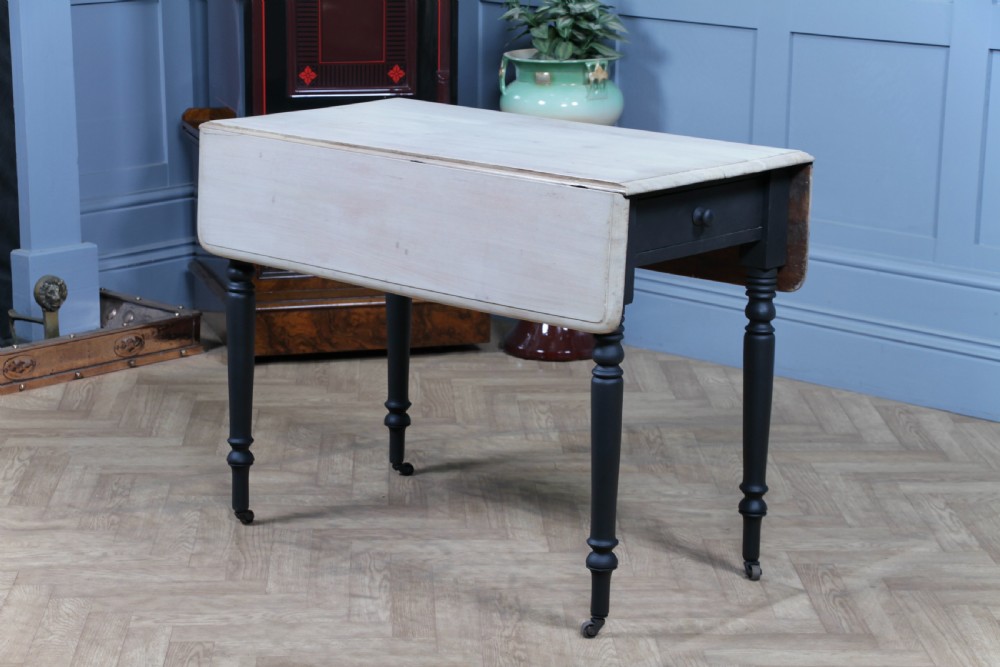 A restored Victorian Pembroke table featuring a bleached mahogany drop-leaf top and a black painted frame with turned legs on brass castors. View XIV
