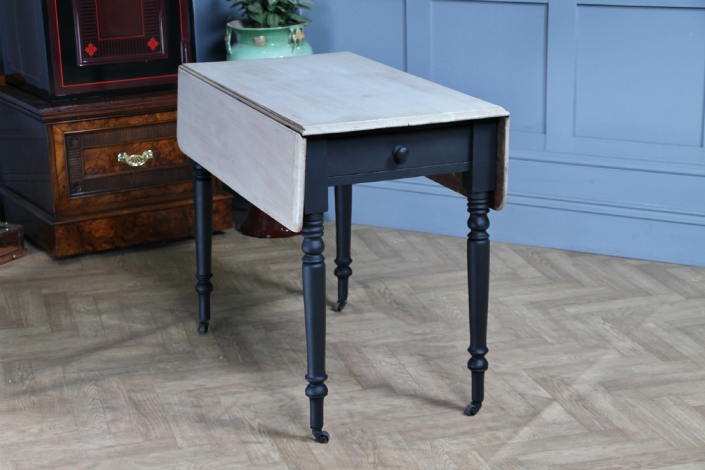A restored Victorian Pembroke table featuring a bleached mahogany drop-leaf top and a black painted frame with turned legs on brass castors. View XX