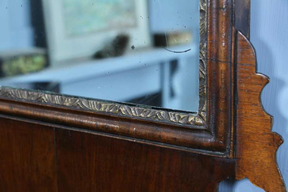 A George III walnut wall mirror featuring silhouette scrollwork, a pierced crest with a gilded plume motif, and a glass plate with visible oxidisation. View VII