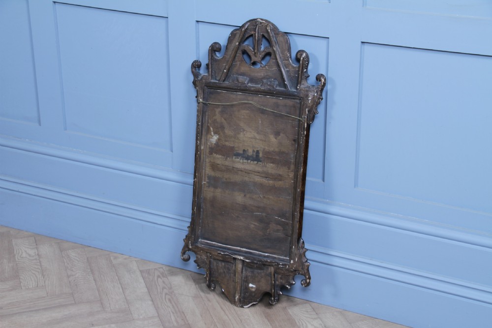 A George III walnut wall mirror featuring silhouette scrollwork, a pierced crest with a gilded plume motif, and a glass plate with visible oxidisation. View XI