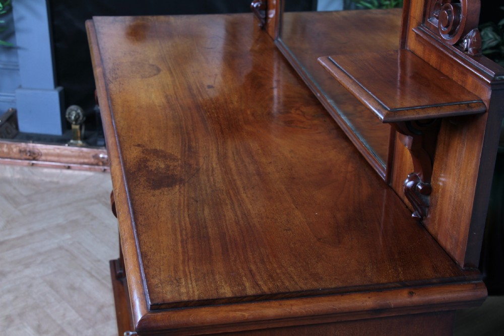 A Victorian mahogany mirror-back sideboard featuring two panelled cabinet doors, upper drawers, tiered side shelves, and a decorative carved cresting. View IX