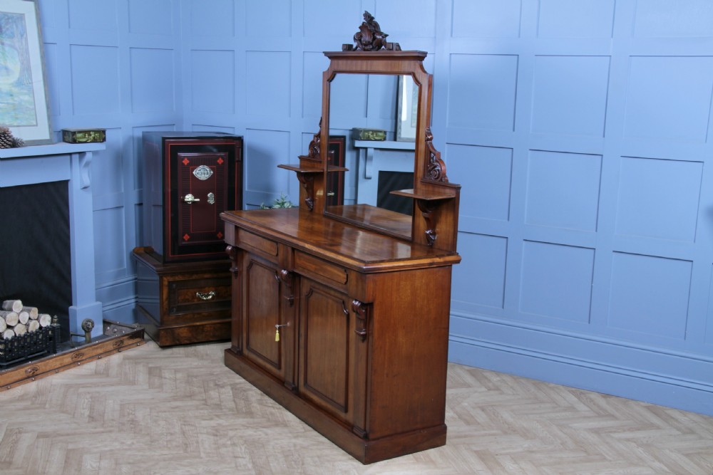 A Victorian mahogany mirror-back sideboard featuring two panelled cabinet doors, upper drawers, tiered side shelves, and a decorative carved cresting. View XI